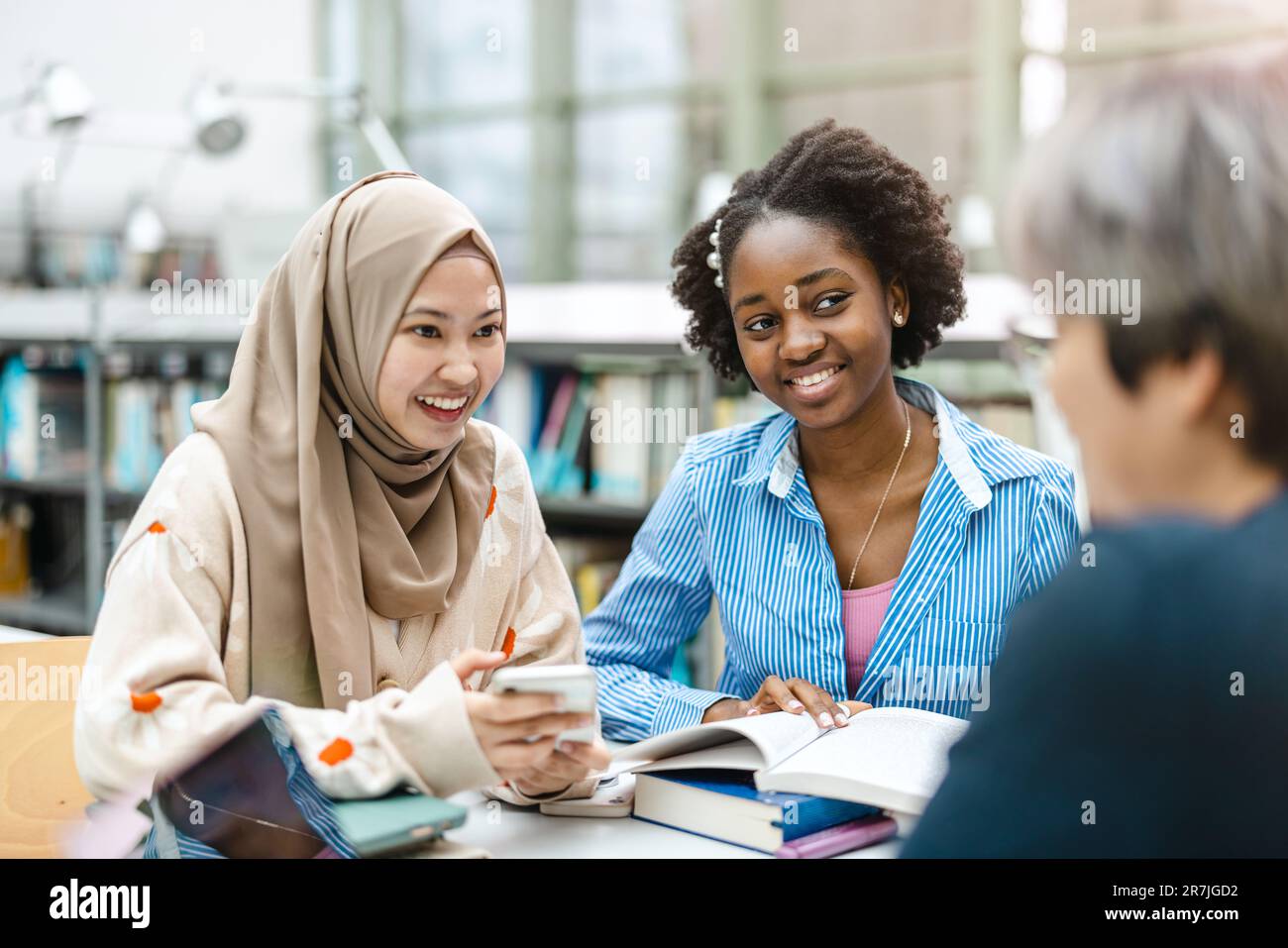 Multiethnic group of students sitting in a library and studying ...