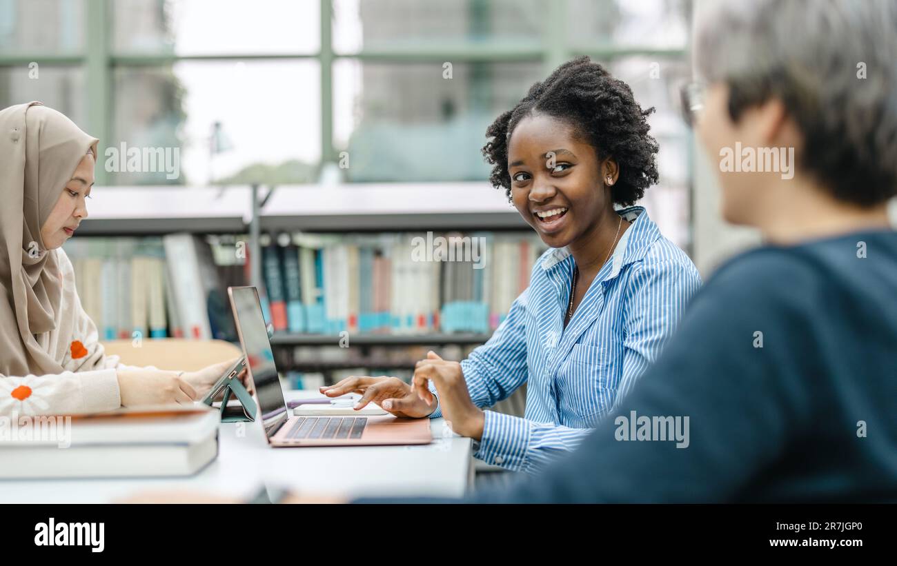 Multiethnic group of students sitting in a library and studying ...