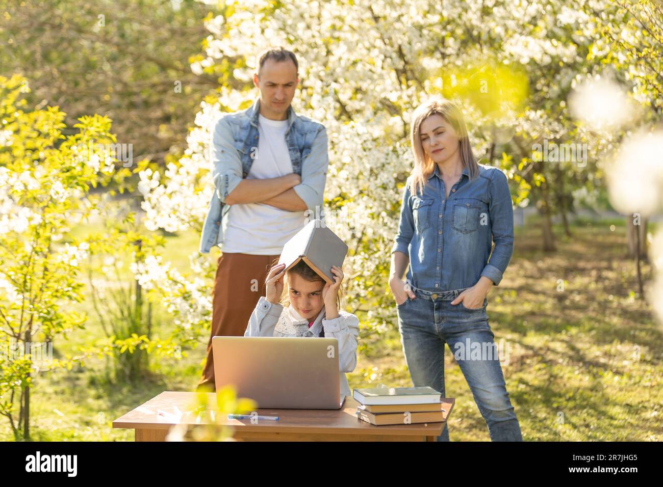 little girl with strict parents studying on laptop outdoor Stock Photo