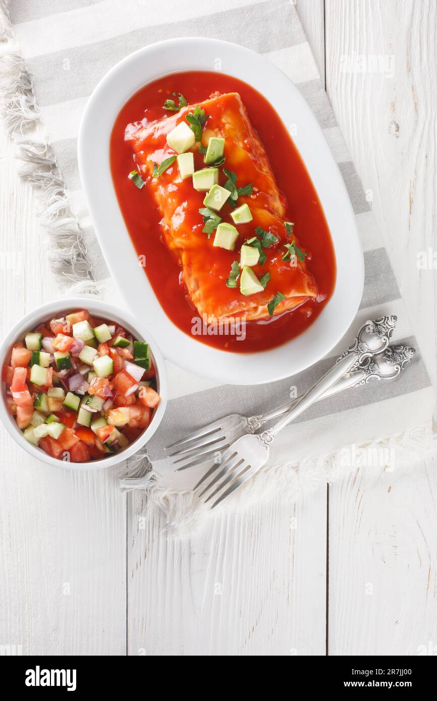Mexican wet burrito platter with red enchilada sauce, refried beans