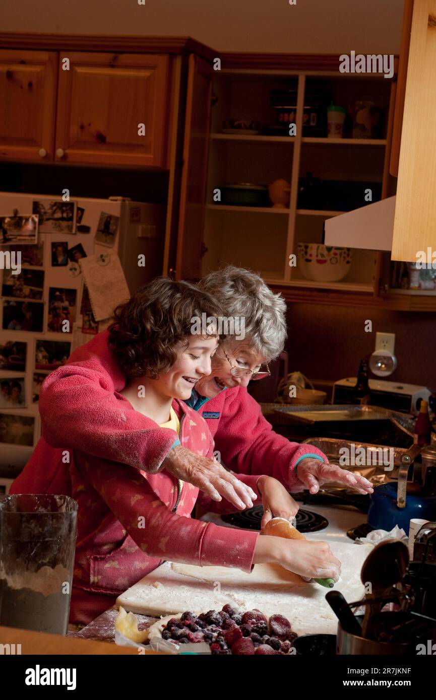 A grandmother teaches her thirteen year old grand daughter to make pie crust from scratch in a cottage in Ontario, Canada. Stock Photo