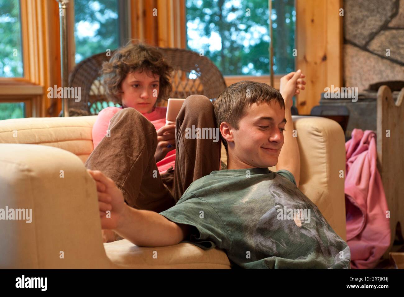 Children enjoy some leisure time on the couch in the living room of their home in Toronto, Canada/ Stock Photo