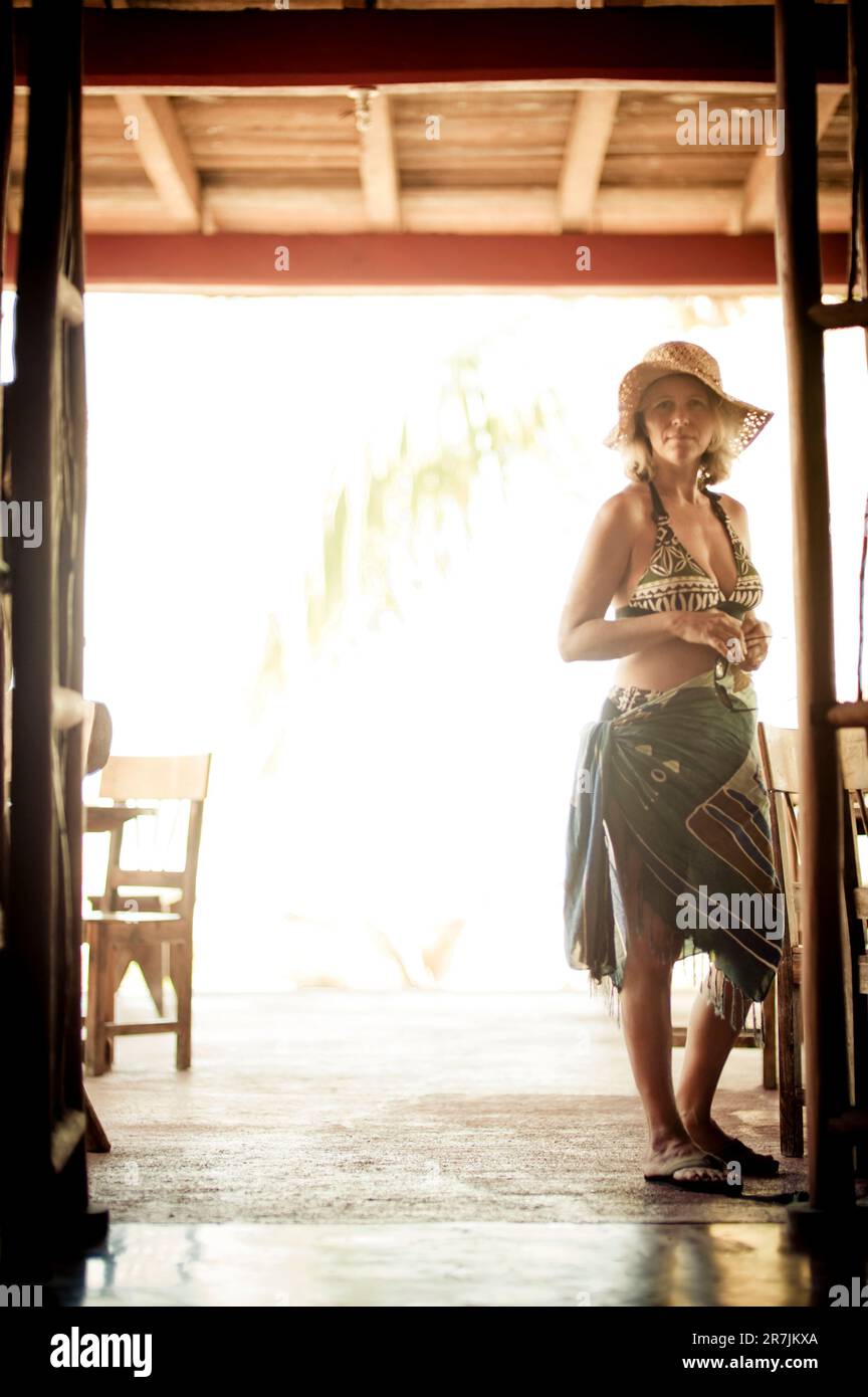 A woman in straw hat and beach attire at the entrance to a beach side cantina in Mexico. Stock Photo