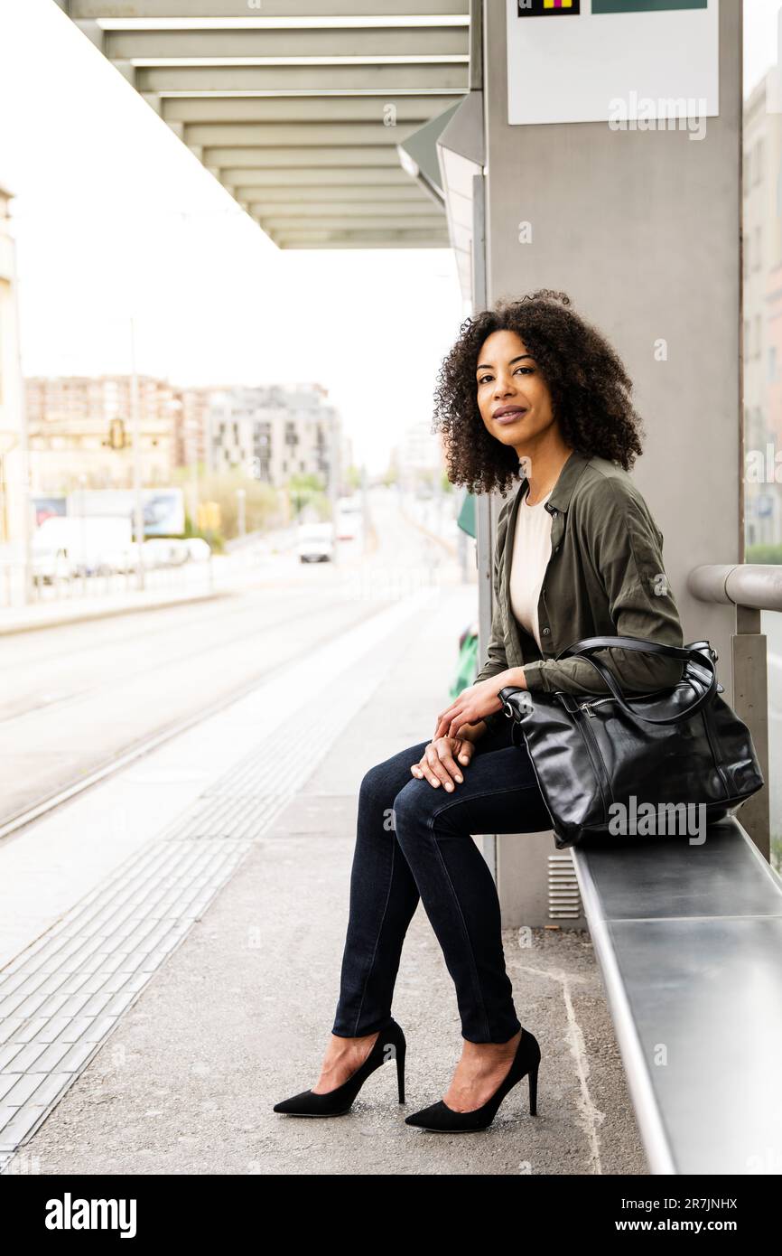 Young female waiting sitting on a tram platform. Stock Photo