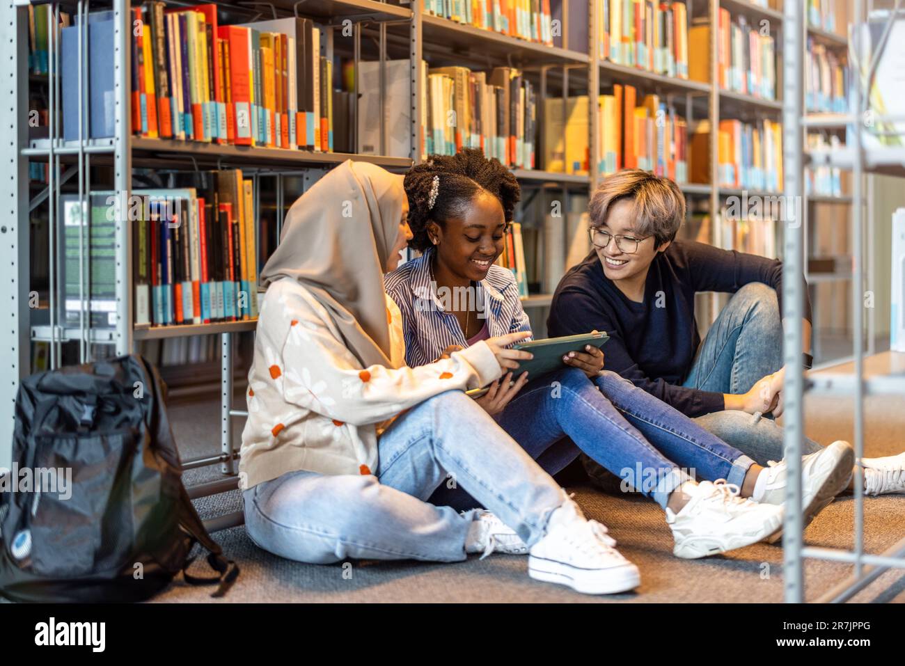 Multiethnic group of students sitting in a library and studying ...