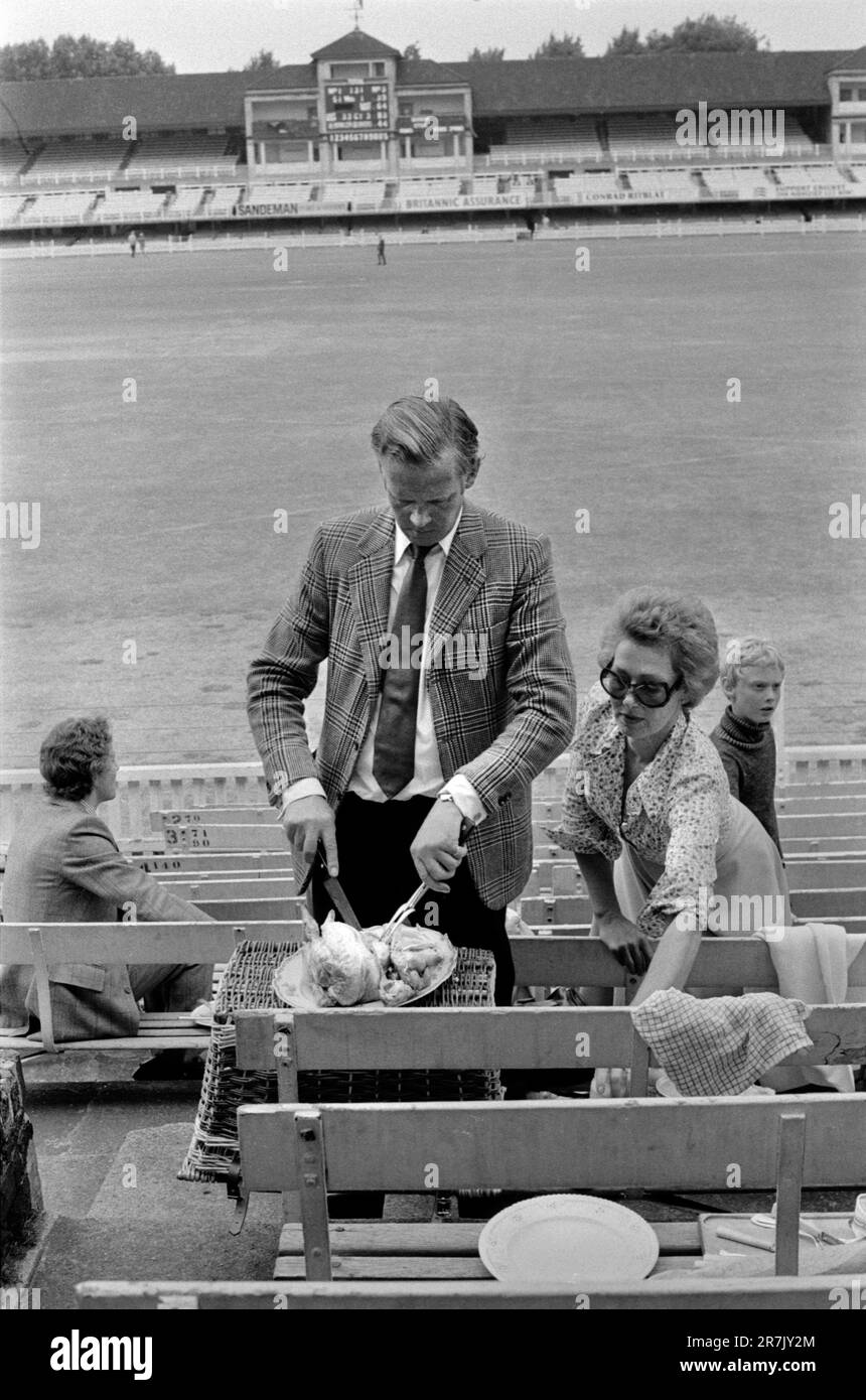 Cutting a Roast Chicken. Eton v Harrow annual cricket match at Lords Cricket Ground. Parents, father carving the cold roast chicken and mother preparing for their picnic  with their son. Its half time and time for lunch.  St Johns Wood, London, England circa June 1975. 1970s UK HOMER SYKES Stock Photo