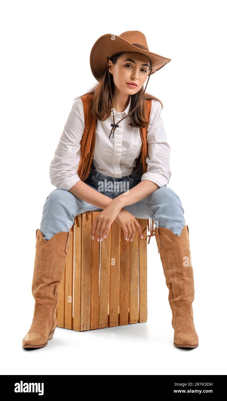 Beautiful cowgirl sitting on white background Stock Photo - Alamy