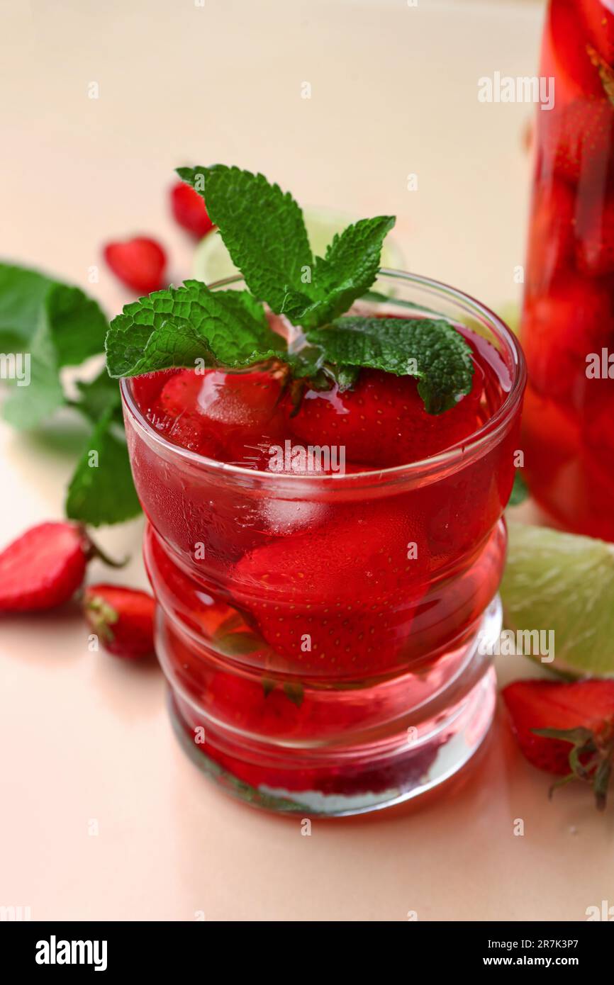 Glass of infused water with strawberry and mint on beige background ...