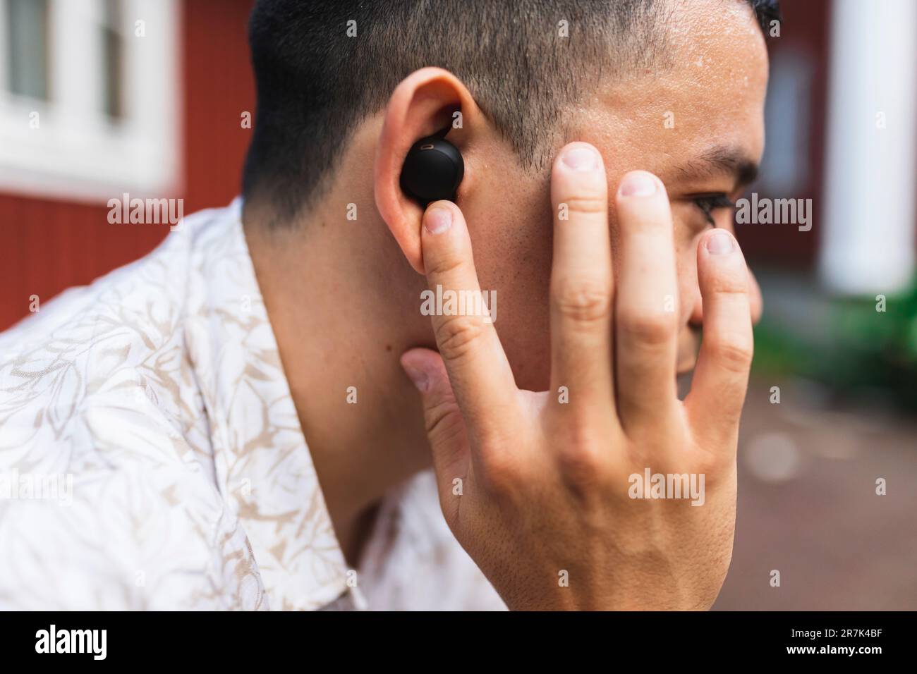 Young man adjusting in-ear headphones Stock Photo