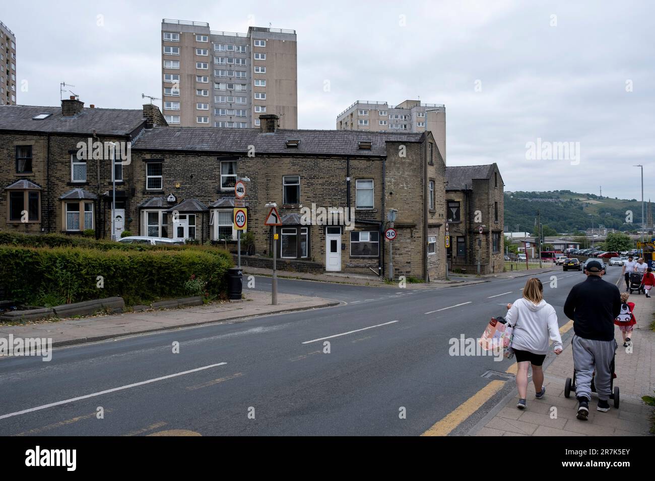 People push prams past old mill workers cottages within the terraced