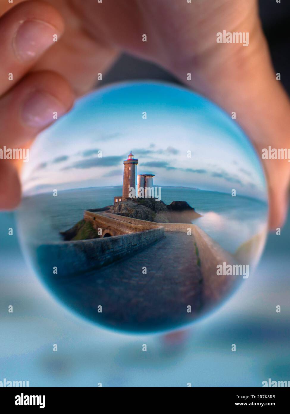 Lighthouse Ball A person holding a glass ball, with the reflection of a lighthouse on ...