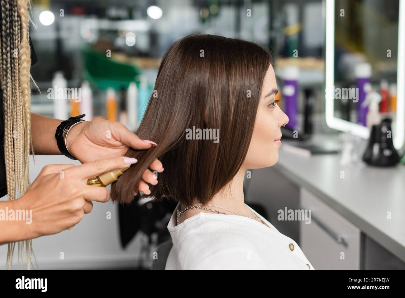 beauty salon work, professional hair stylist with braids applying oil