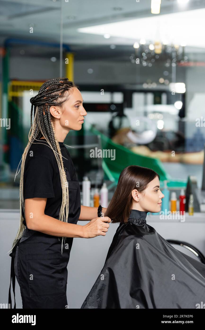 beauty industry, hair stylist with braids wearing hairdressing cape on