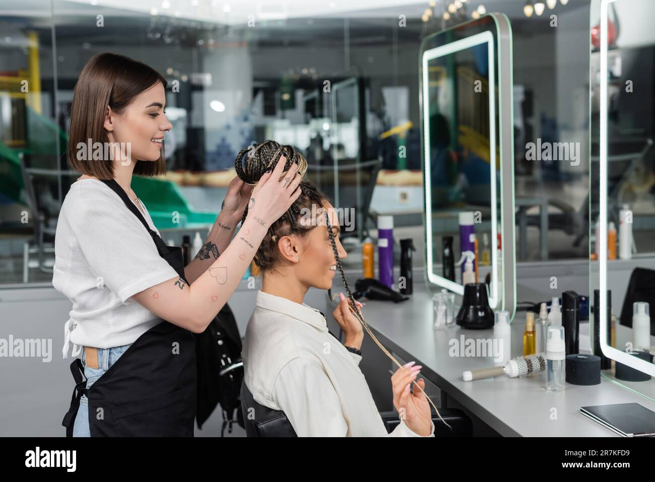 hair make over, happy hair stylist doing hair of female client with braids, cheerful women, client satisfaction, customer in salon, beauty service, sa Stock Photo