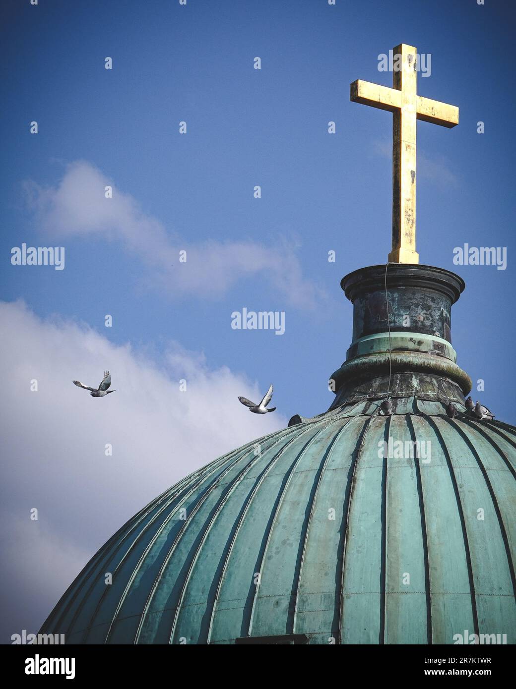 A single aircraft flying in the sky above a domed structure with a cross on its peak Stock Photo