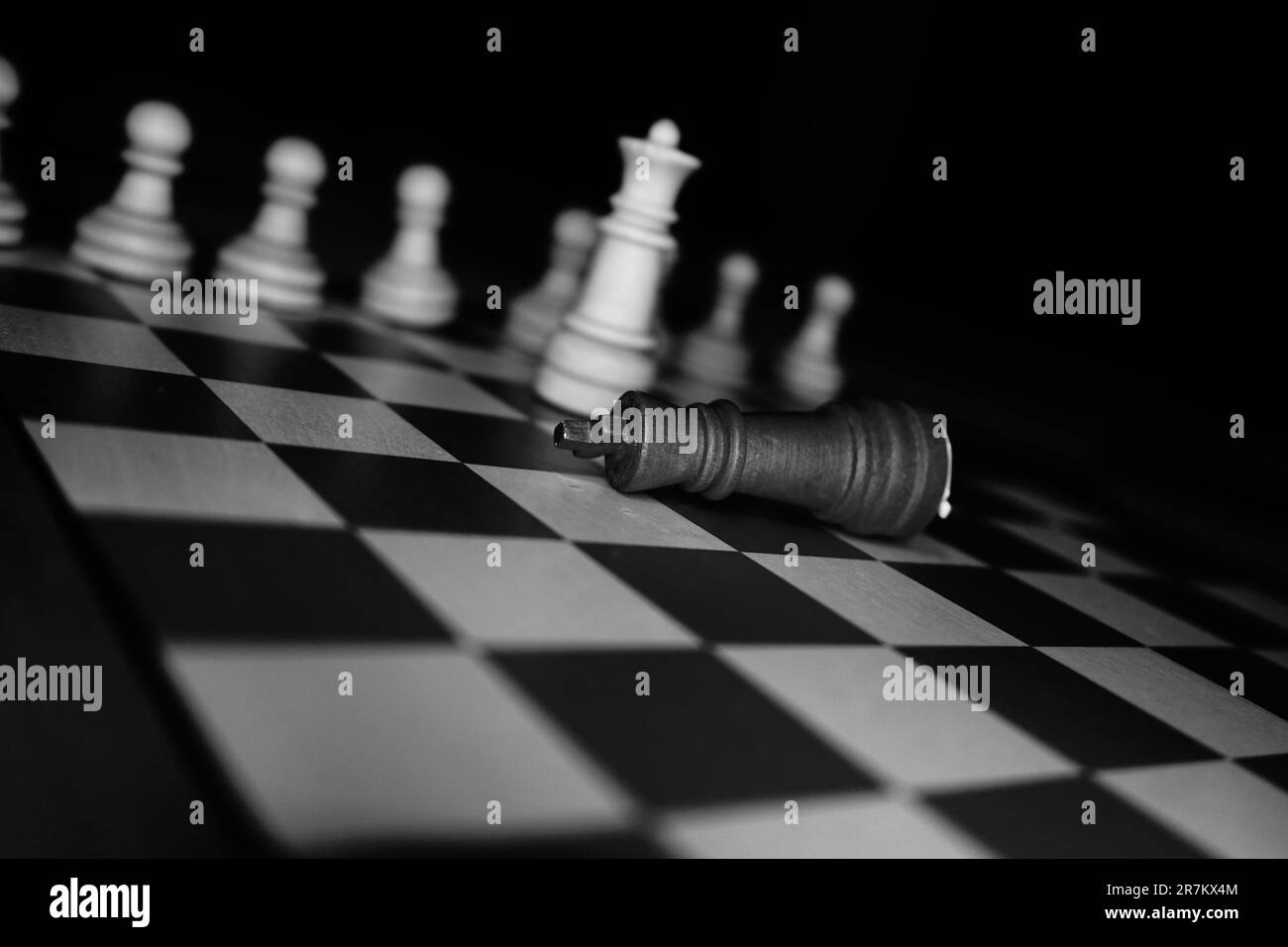 A black and white chess board with various pieces arranged in various positions, white the king is fallen Stock Photo