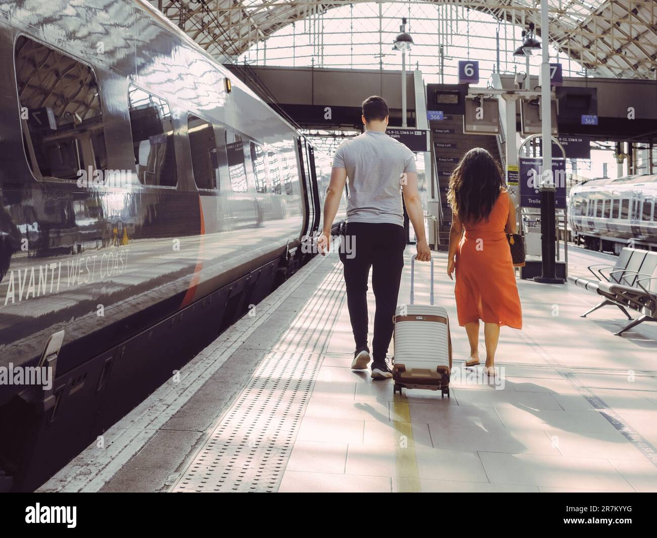 Two commuters or passengers on a train platform with suitcase luggage