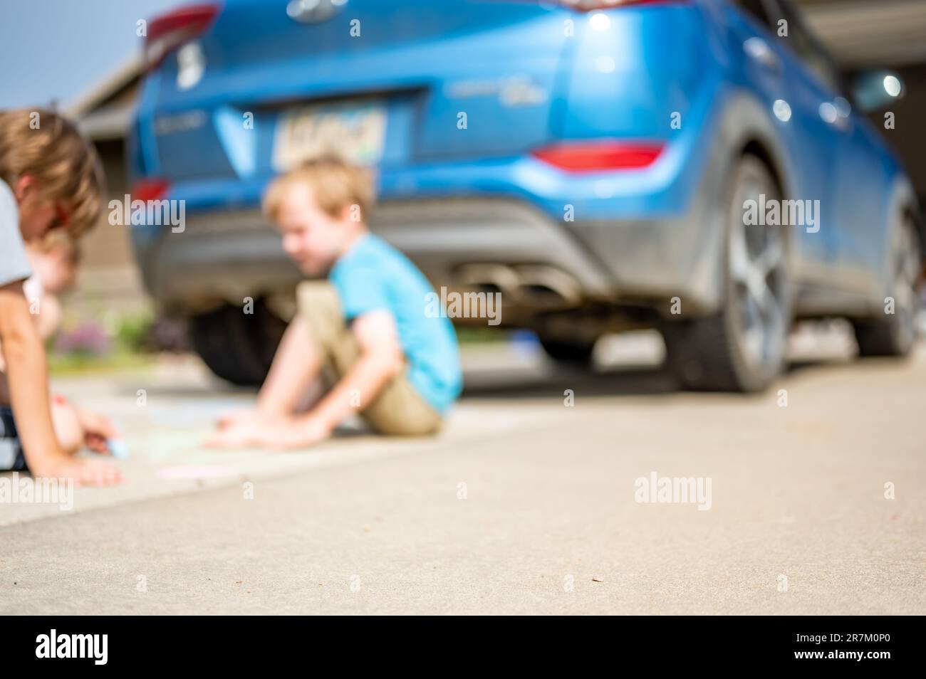 Children sitting on a driveway behind a vehicle in a blind spot out of ...