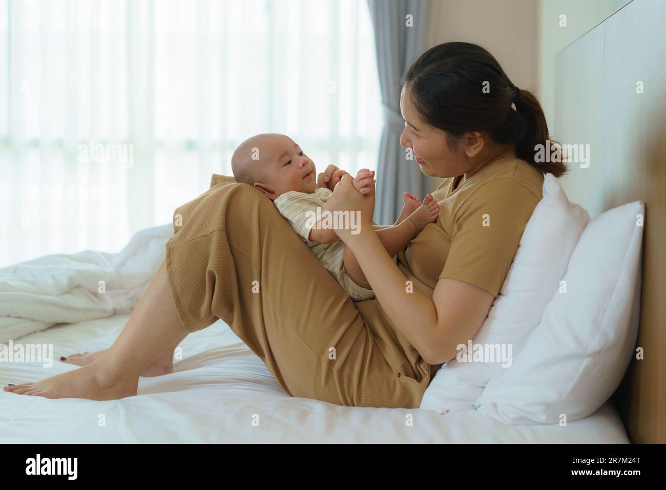 Asian mother playing with her newborn baby in bedroom at home. to promote family relations and good development of the baby Stock Photo