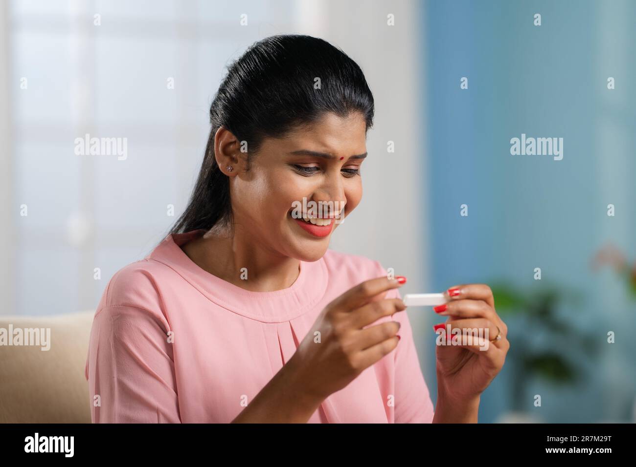 Excited happy Indian woman celebrating after seeing positive pregnant result at home - concept of anticipation, parenthood and good news. Stock Photo