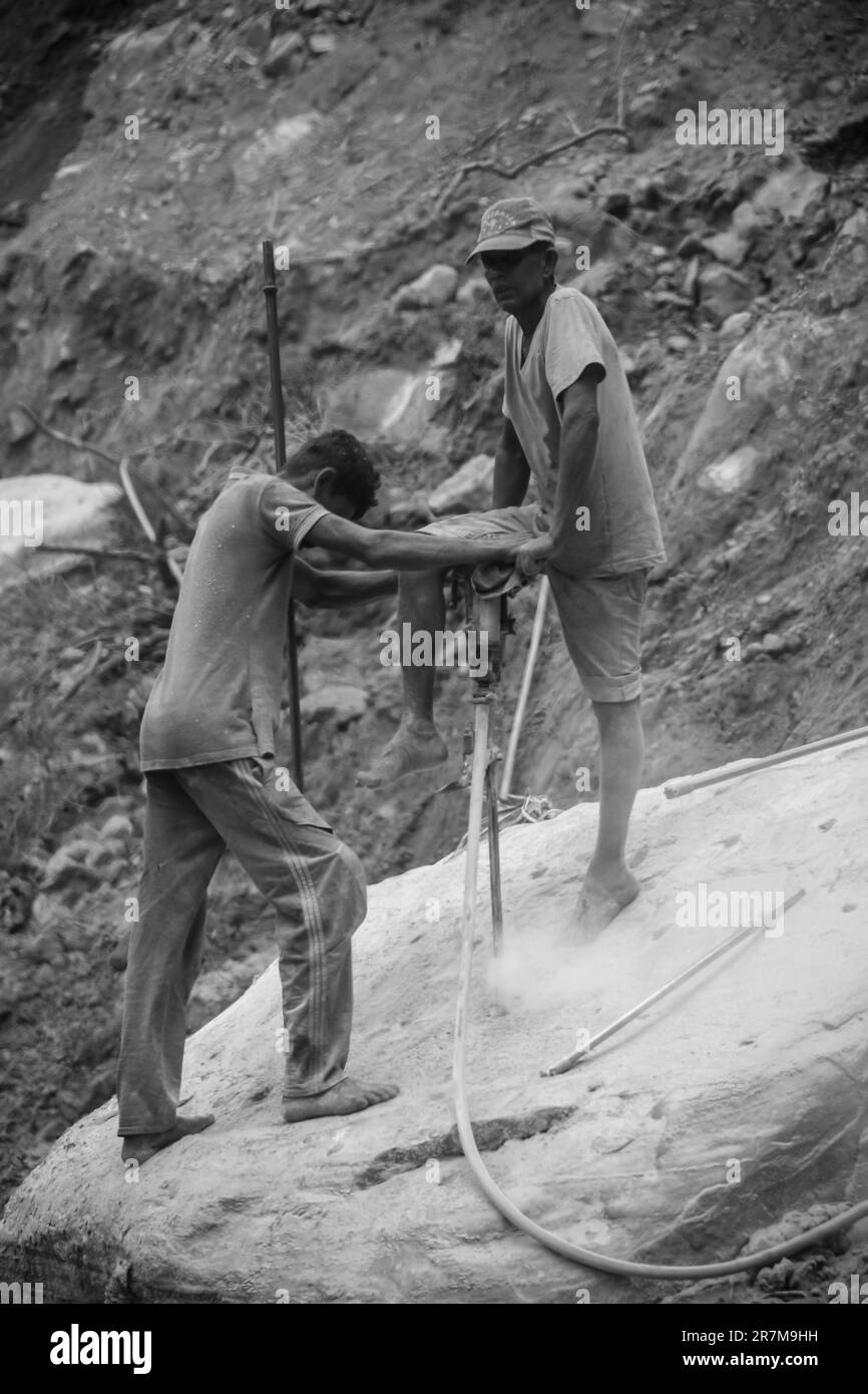 A grayscale of Tow People work Hard Rock Stone Drill Machine Stock Photo