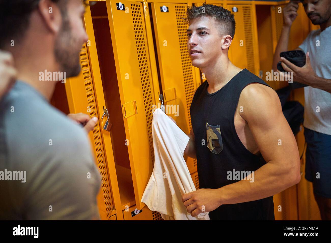 Young men in the locker room, having a conversation together before working out. Health