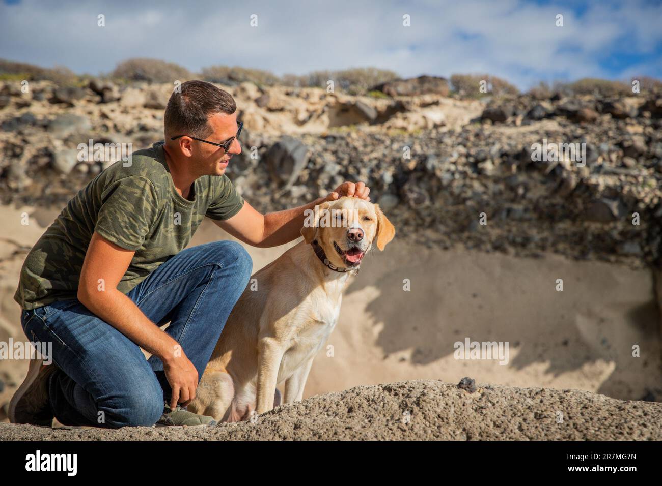 A dog and his owner together, the owner gives the animal a cuddle