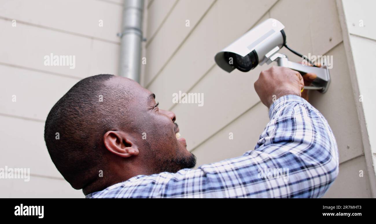 African American Handyman With CCTV Camera, Security System Stock Photo
