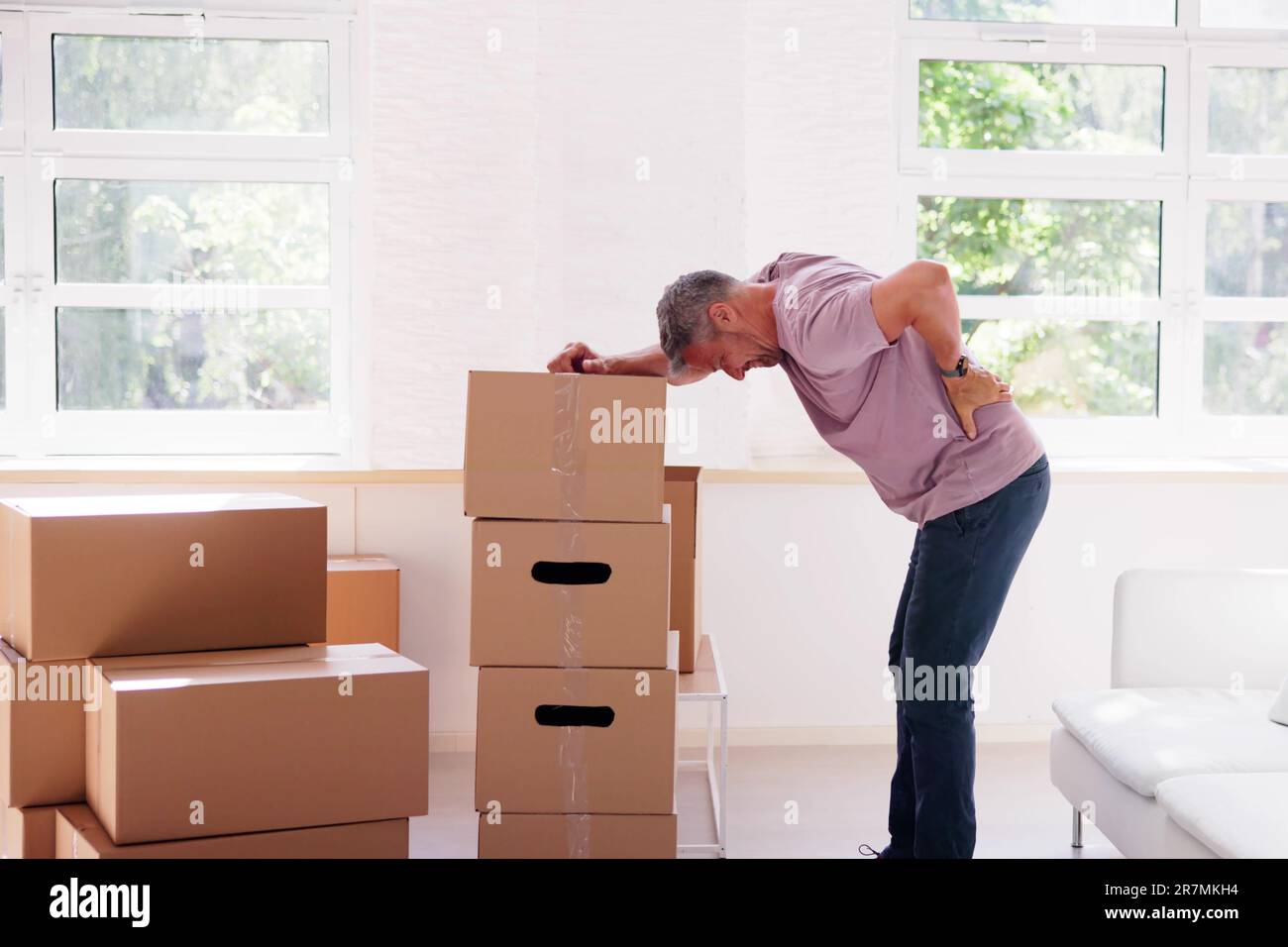 Lifting Heavy Box With Back Pain. Man At Home Stock Photo