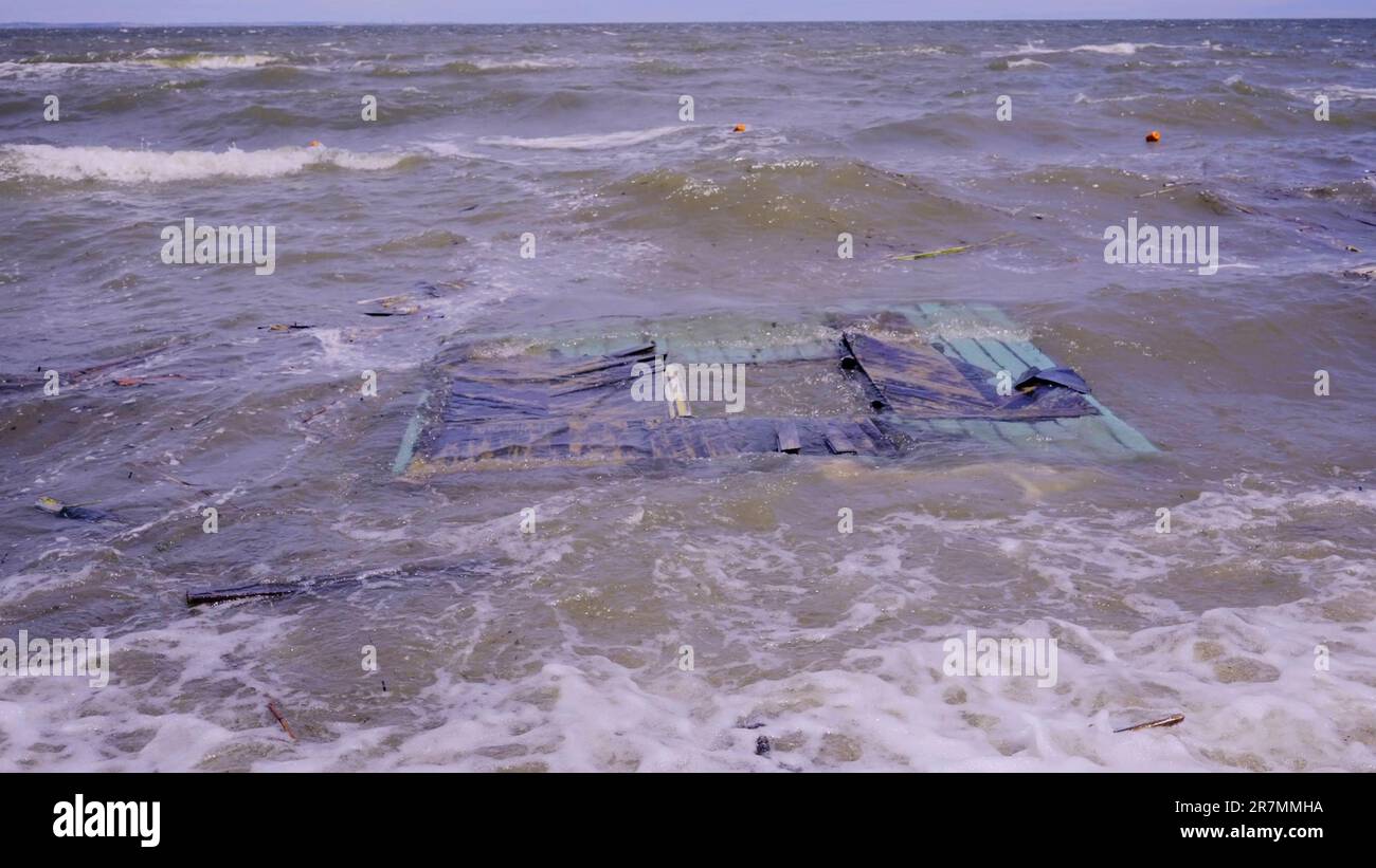 Part of wall of house floats near shore, floating debris has reached