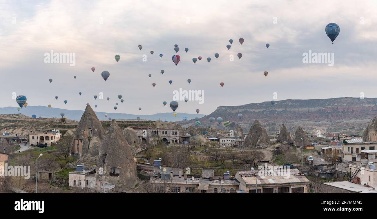 A picture of hot air balloons flying over the Goreme Historical National Park and the town of Goreme at sunrise. Stock Photo