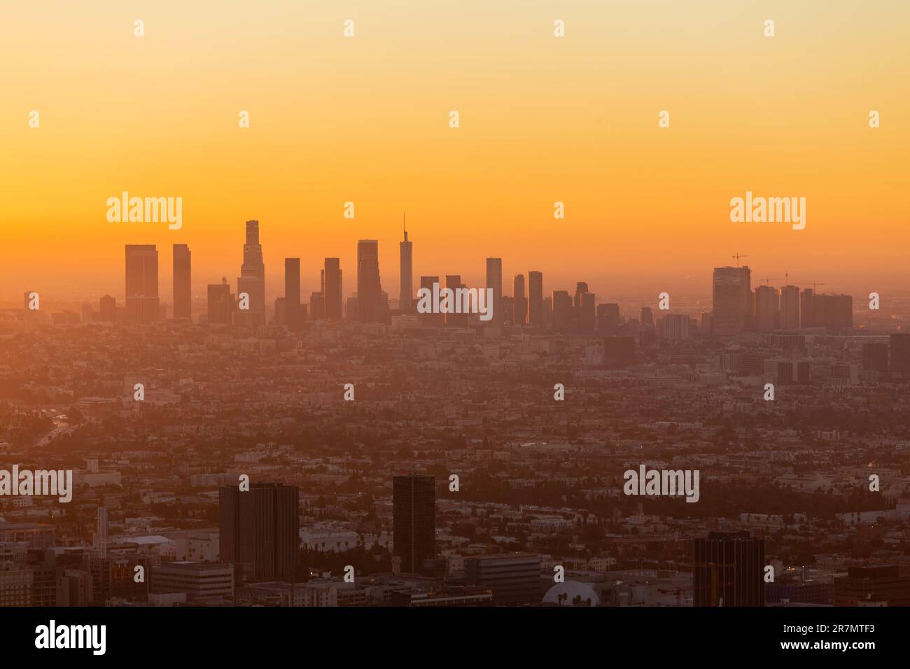 Smoggy orange sunrise cityscape view of Los Angeles and Hollywood from hilltop in the Santa Monica Mountains. Stock Photo