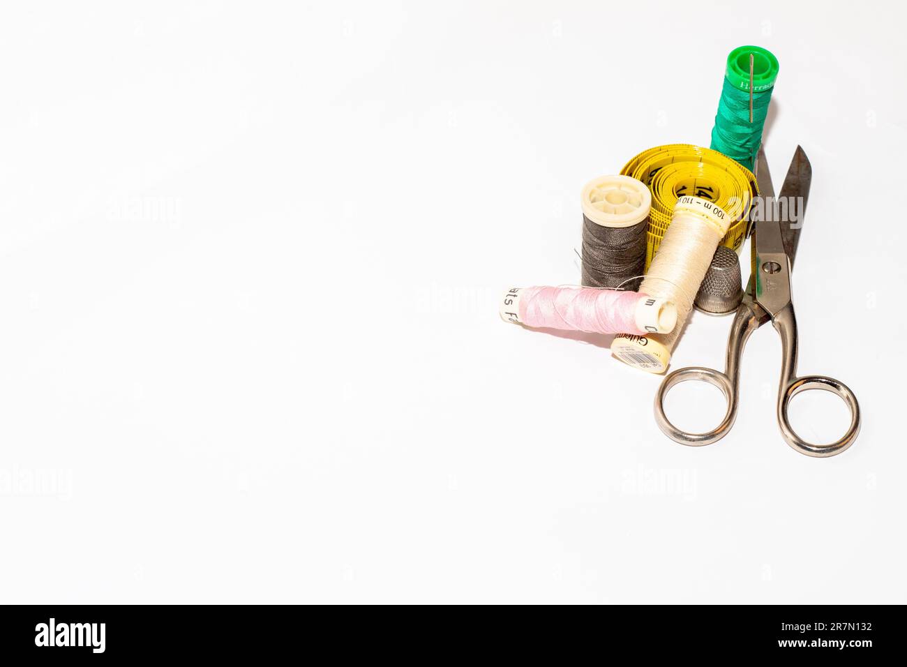 The spools of thread of different colors with scissors, and a tape ...