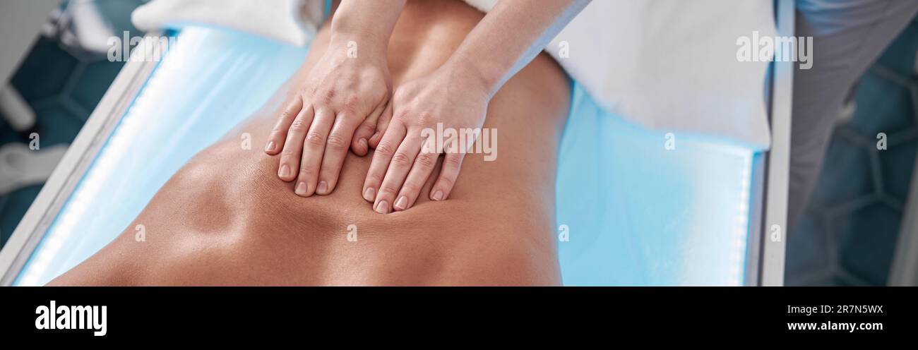 Therapist massages back of male patient in contemporary clinic office closeup Stock Photo