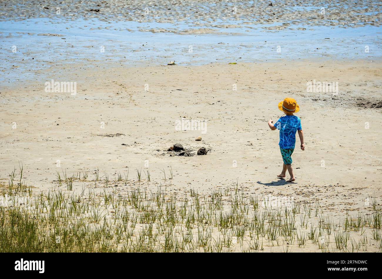A boy on this first warm day of Spring heads out for a walk on the beach, strutting like he own the whole area. Maybe someday he will. Stock Photo