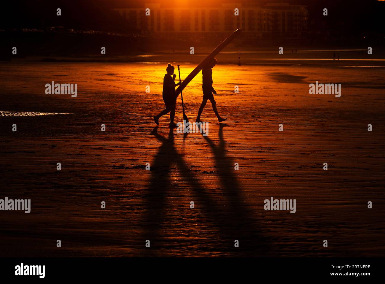 Scarborough, North Yorkshire, UK. 16th June 2023. Paddle boarders walk out to the sea at sunset at North Bay, Scarborough, North Yorkshire. Neil Squires/Alamy Live News Stock Photo