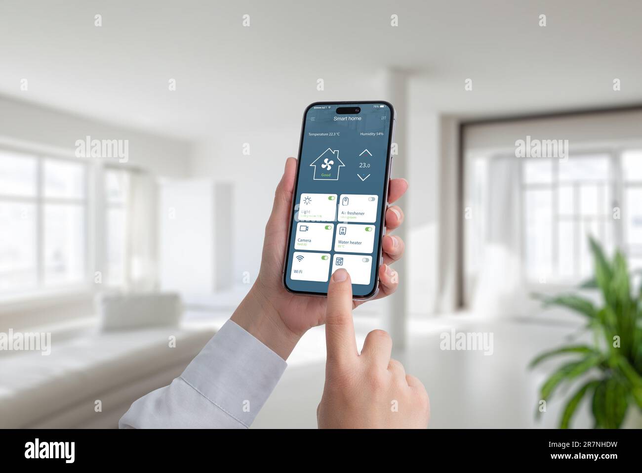 Person controls the temperature and lighting in the house with the help of an app on a mobile phone. A modern smart home application with the most imp Stock Photo