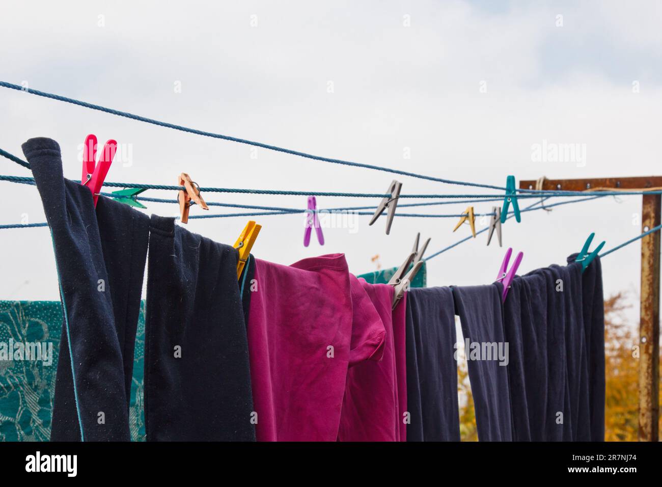 A clothespin hangs on the washing line. A rope with clean linen and clothes outdoors on the day of the laundry. Against the background of green nature Stock Photo