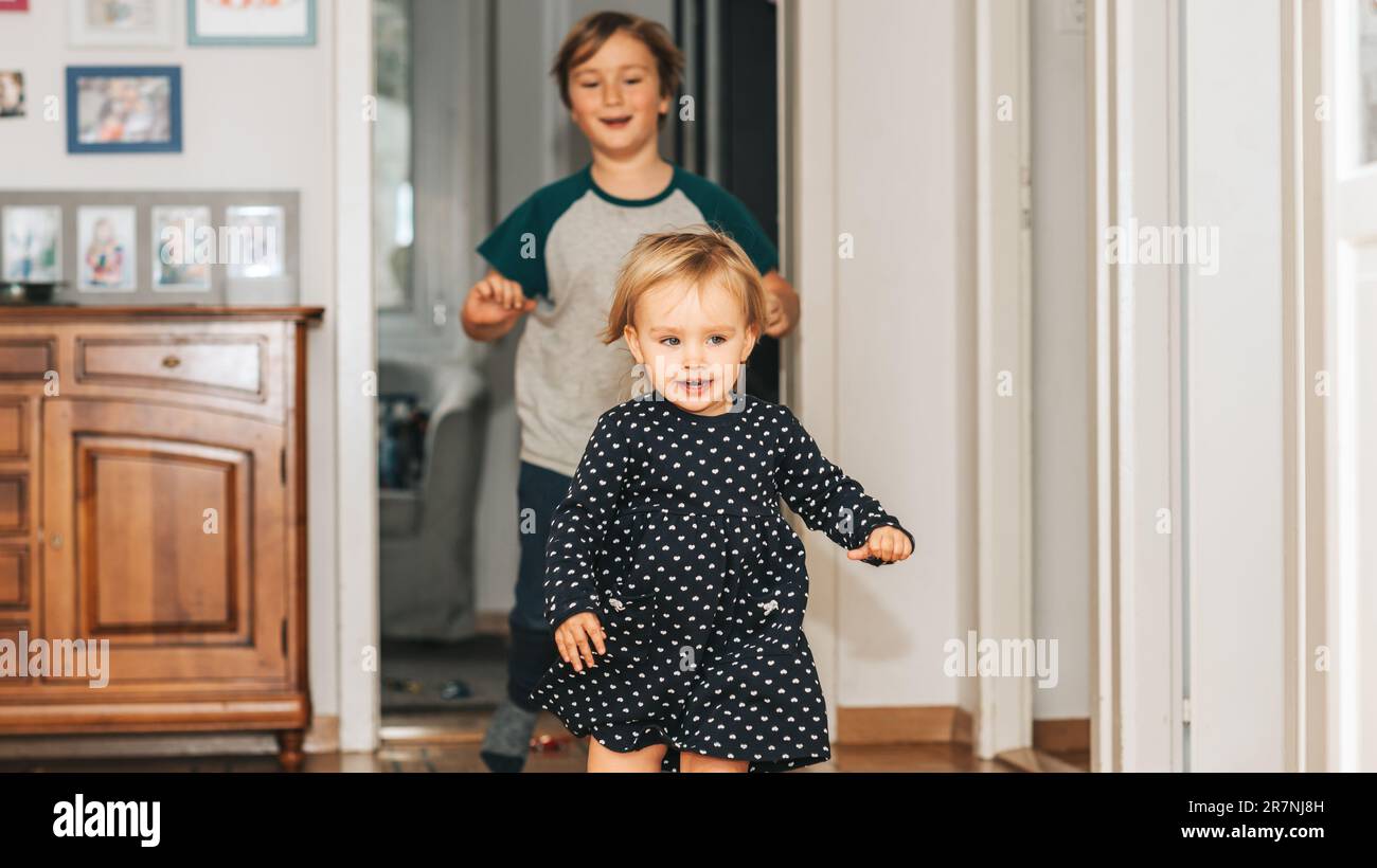 Two funny kids playing together at home, running and jumping Stock Photo