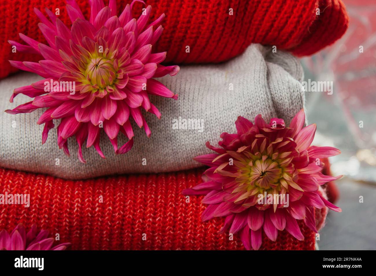 Pattern of colorful knitted sweaters closeup. Handmade merino wool product. A stack of folded clothes with flowers Stock Photo
