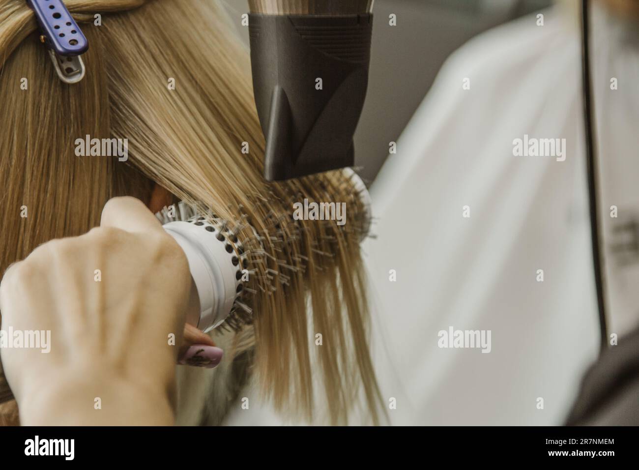 Close up of hairdresser hands drying human hair with equipment. Woman holding a comb. close-up. Macro photo Stock Photo