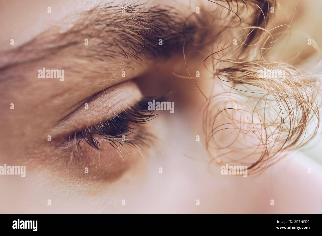 male eye close up. a curl of curly hair hangs over a man's face. thoughtful look into the void. Stock Photo