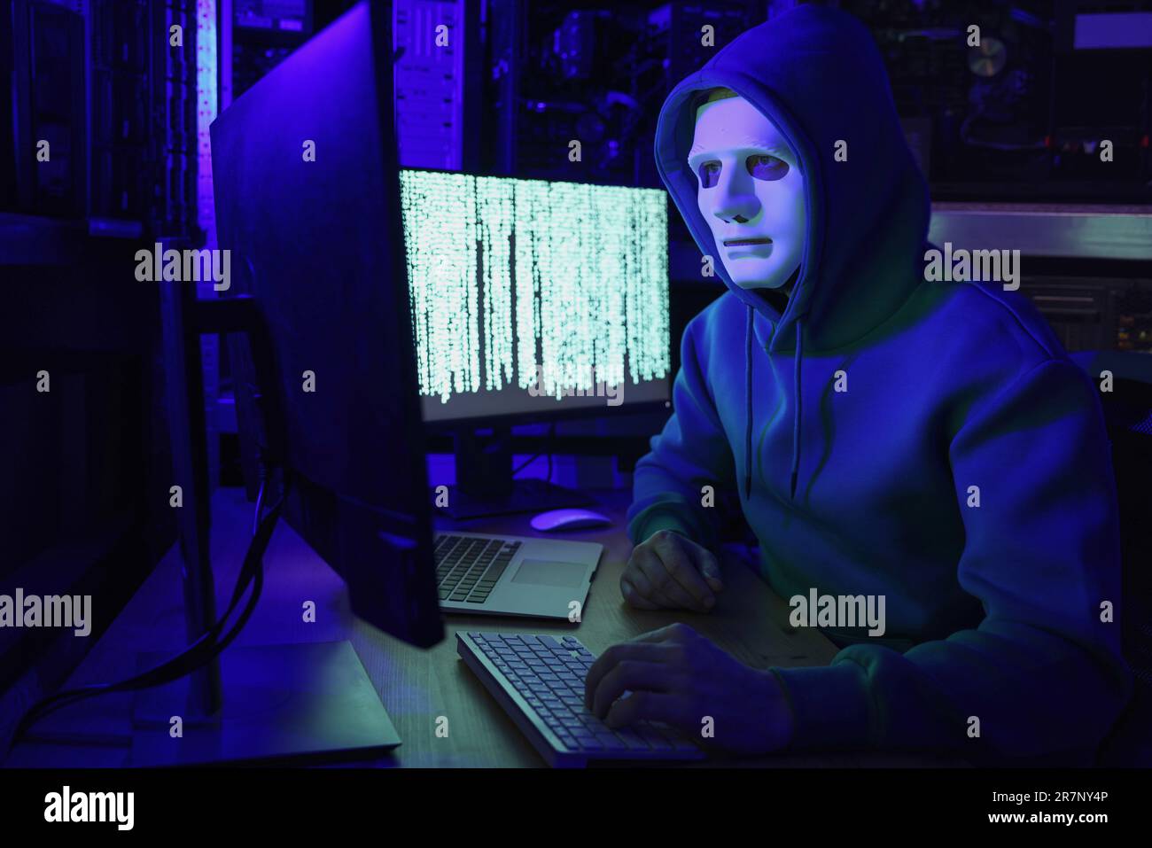 Hacker in mask working with computers in dark room. Cyber attack Stock Photo