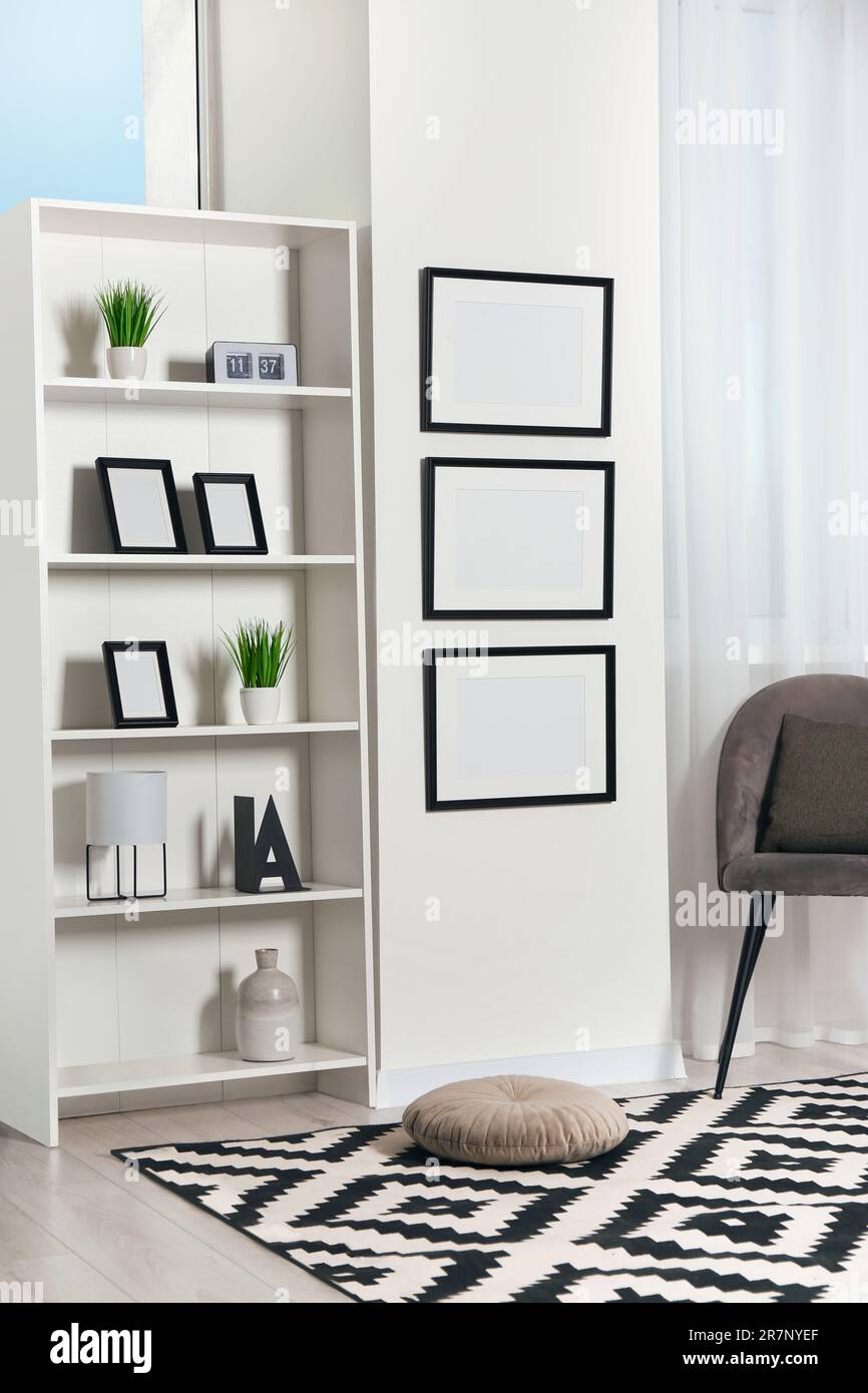 Stylish room interior with empty frames hanging on white wall near