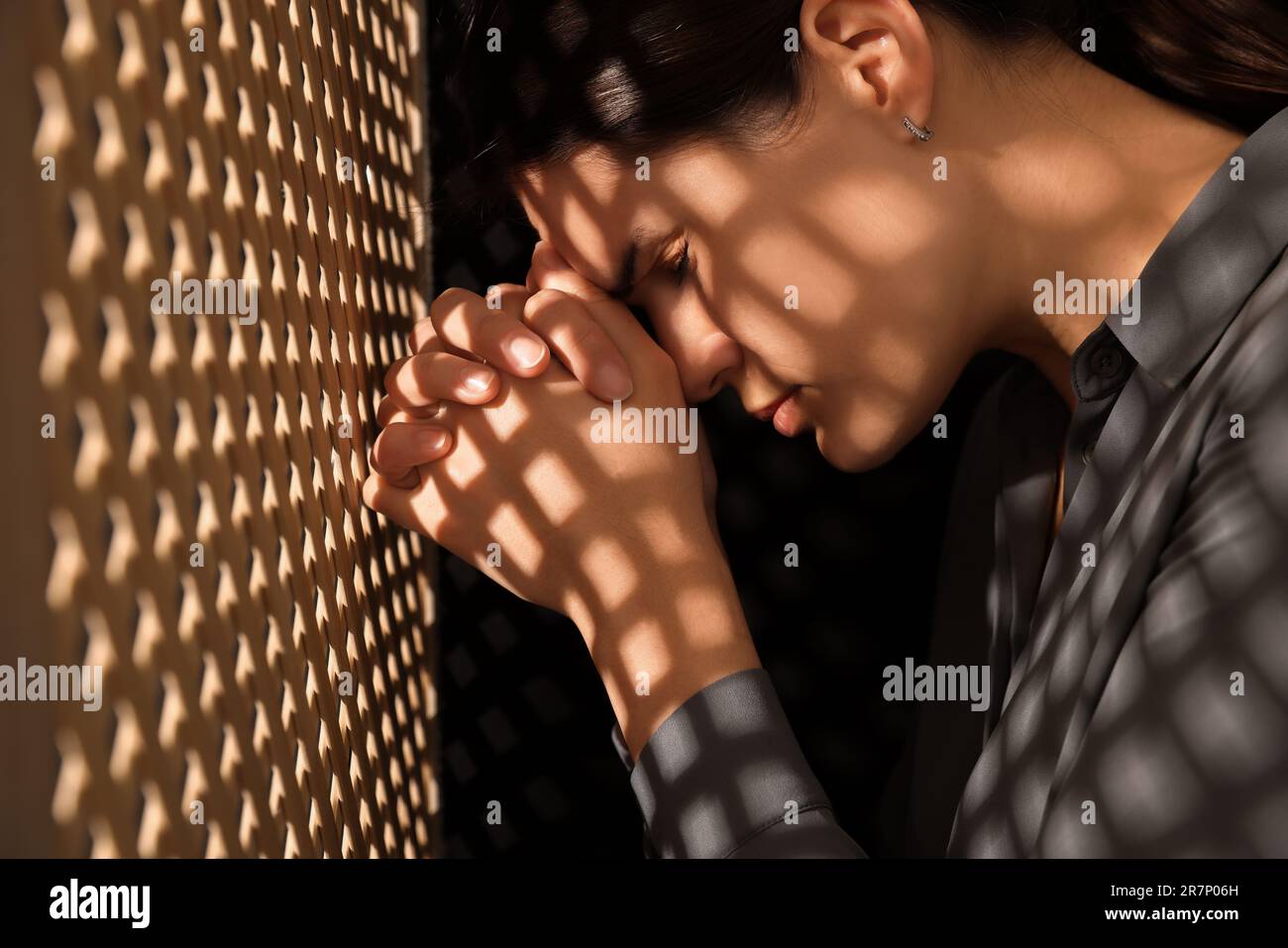 Repentant woman during confession near wooden partition in booth Stock ...