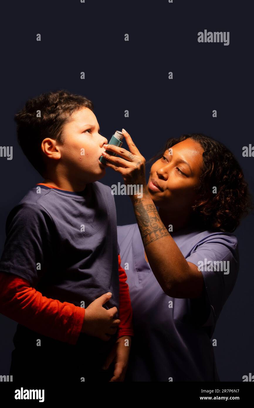 Healthcare professional assisting 7 year old boy using inhaler Stock ...