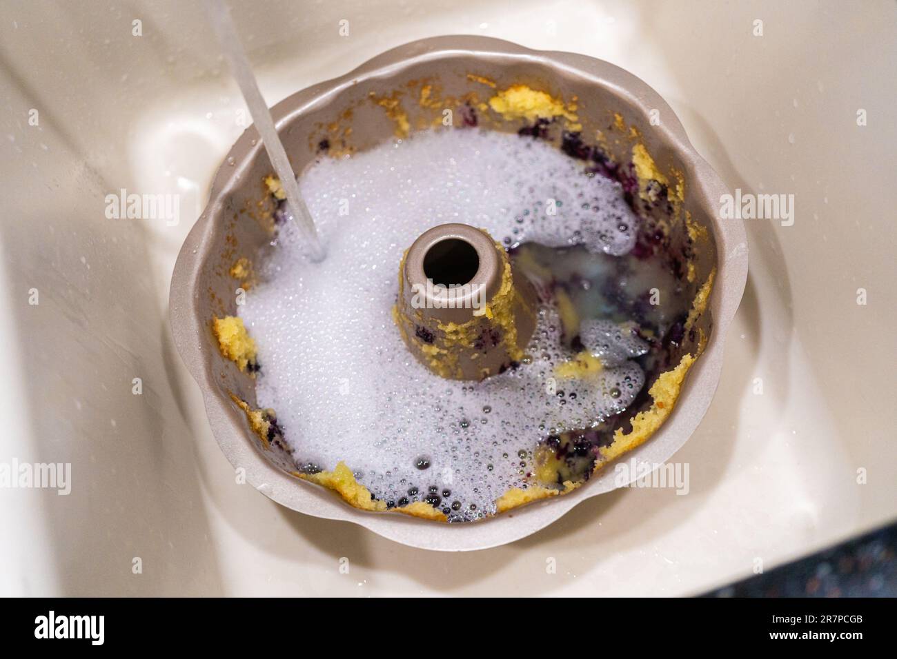 Washing dirty aluminum bundt cake pan Stock Photo by arina-habich