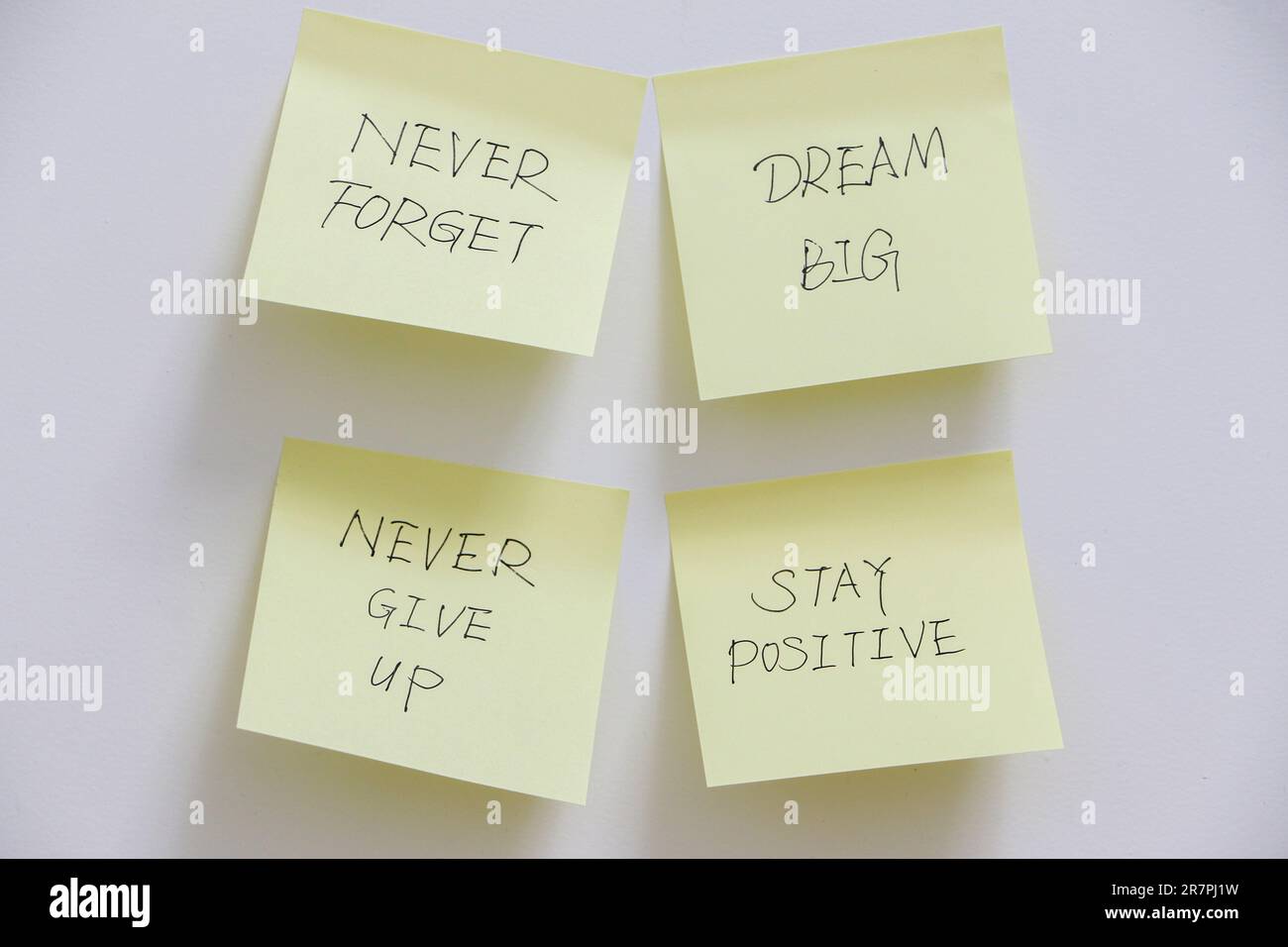 Motivation concept, four yellow sticky notes on white wall with