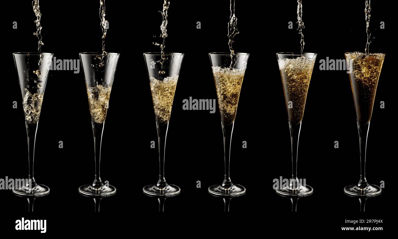 Pouring sparkling wine into a glass on a black reflective background. Stock Photo