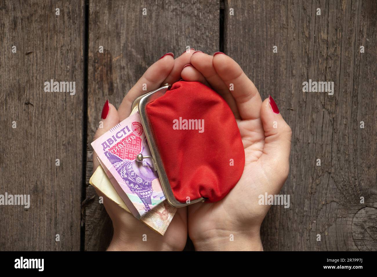 hands hold a red wallet with Ukrainian money on the background of a board Stock Photo